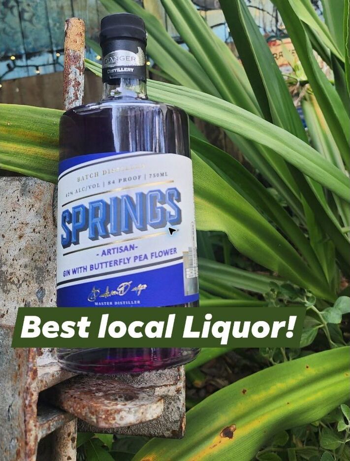 Springs Artisan Gin bottle among tropical plants